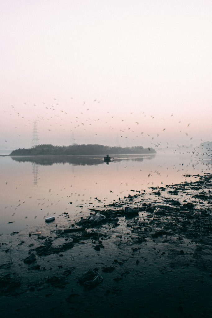 Explore the tranquil silhouette of a boat on the Yamuna River at sunrise, captured in New Delhi, India.